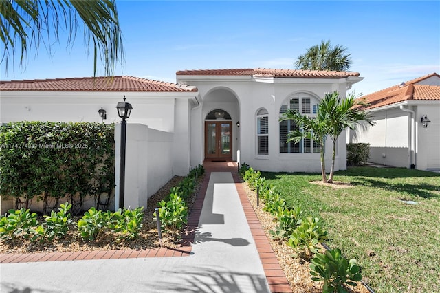 mediterranean / spanish-style house featuring a front lawn and french doors