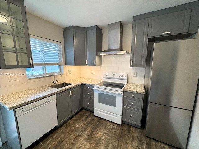 kitchen with white appliances, wall chimney exhaust hood, light stone countertops, and sink