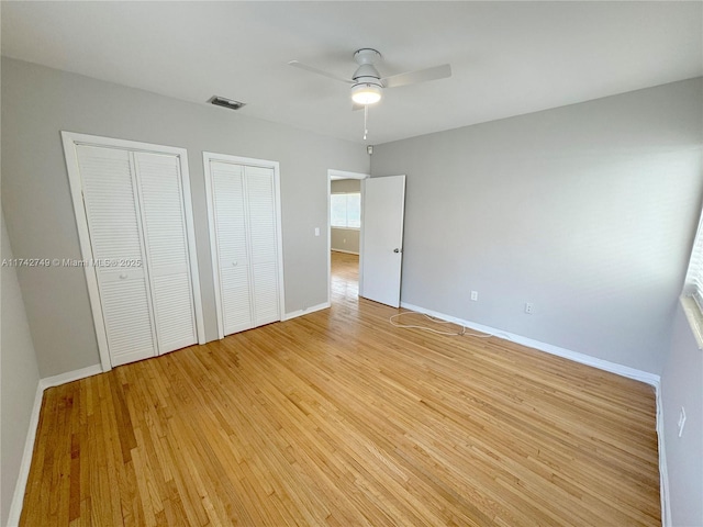 unfurnished bedroom with two closets, ceiling fan, and light hardwood / wood-style flooring