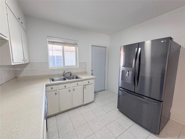 kitchen with sink, stainless steel fridge, tasteful backsplash, white cabinets, and light tile patterned flooring