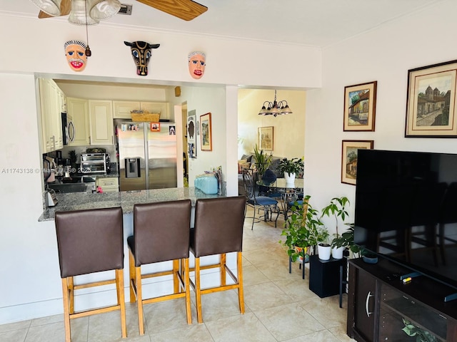 kitchen with a breakfast bar, cream cabinetry, crown molding, appliances with stainless steel finishes, and a peninsula