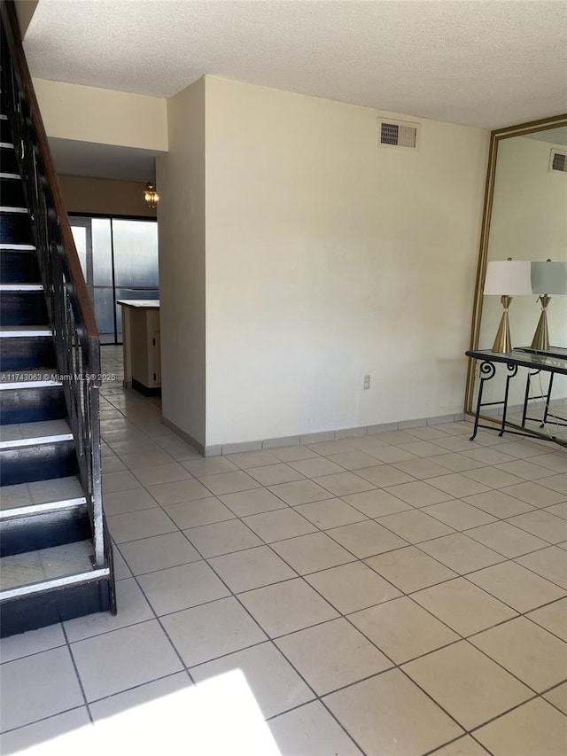 unfurnished room with light tile patterned flooring and a textured ceiling