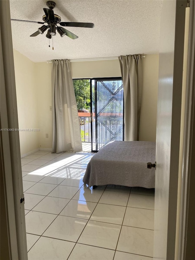 bedroom with ceiling fan, access to outside, tile patterned floors, and a textured ceiling