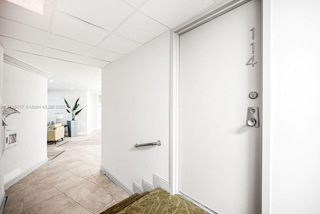 hallway featuring a paneled ceiling and light tile patterned floors