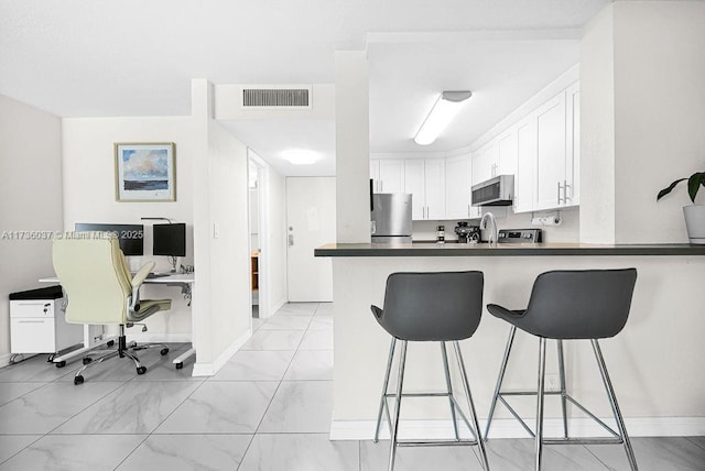 kitchen featuring white cabinetry, a kitchen breakfast bar, stainless steel appliances, and kitchen peninsula