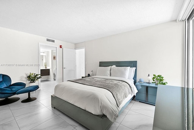 bedroom featuring connected bathroom and a textured ceiling