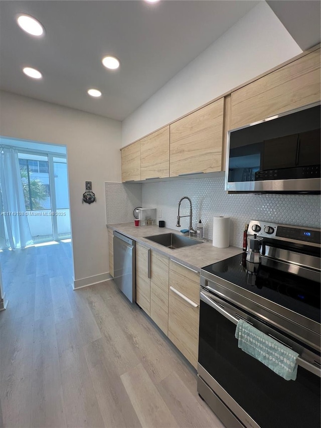 kitchen with stainless steel appliances, light brown cabinetry, sink, and decorative backsplash