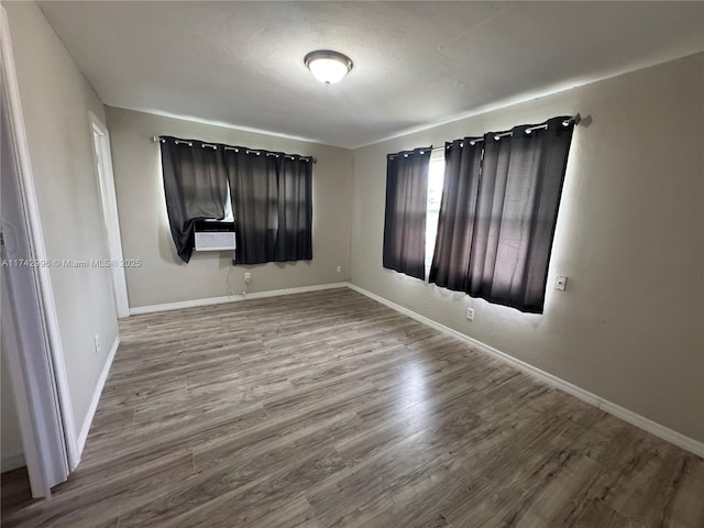 unfurnished bedroom with cooling unit, wood-type flooring, and a textured ceiling