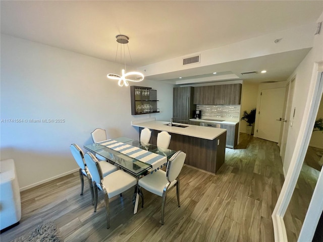 dining area with an inviting chandelier, wood-type flooring, and sink