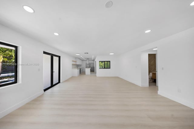 unfurnished living room featuring recessed lighting, baseboards, and light wood finished floors