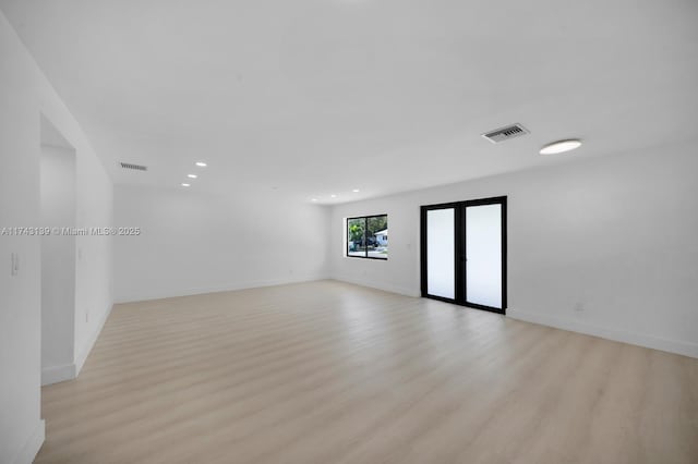 empty room featuring french doors, visible vents, baseboards, and light wood finished floors