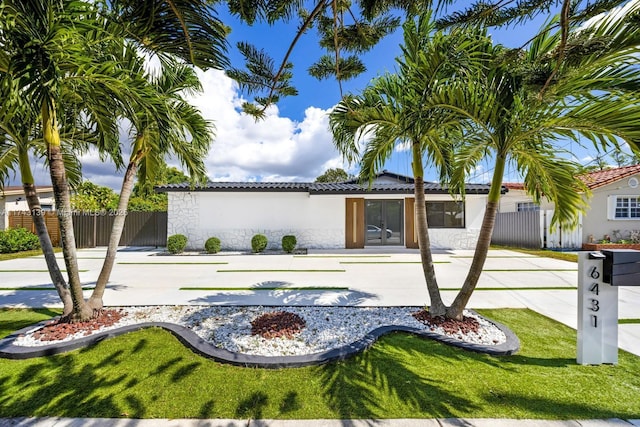 view of front of property featuring a patio area, fence, stucco siding, and a tiled roof