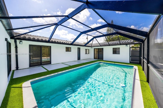 pool with a patio area, glass enclosure, and fence