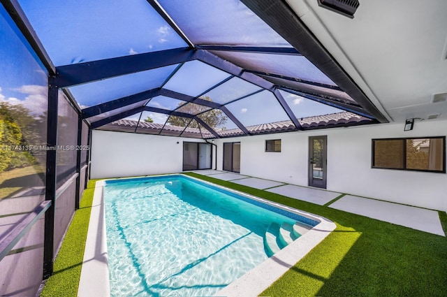 outdoor pool featuring glass enclosure and a patio