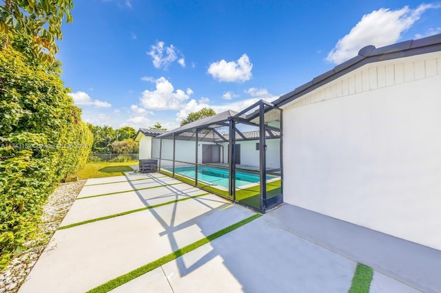 view of patio / terrace with glass enclosure, fence, and an outdoor pool