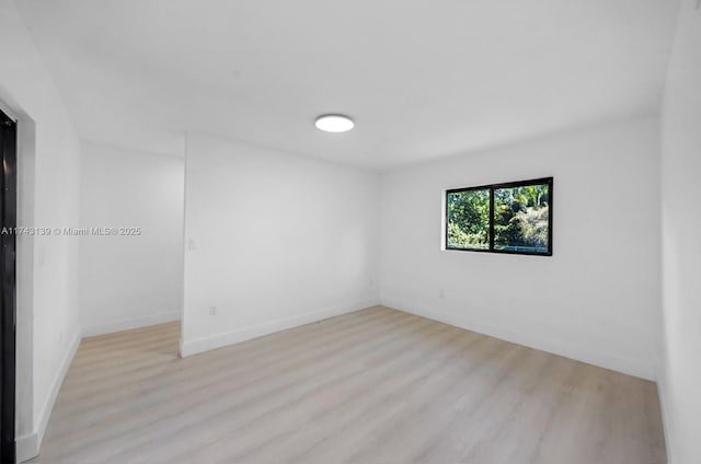 unfurnished room with light wood-type flooring and baseboards