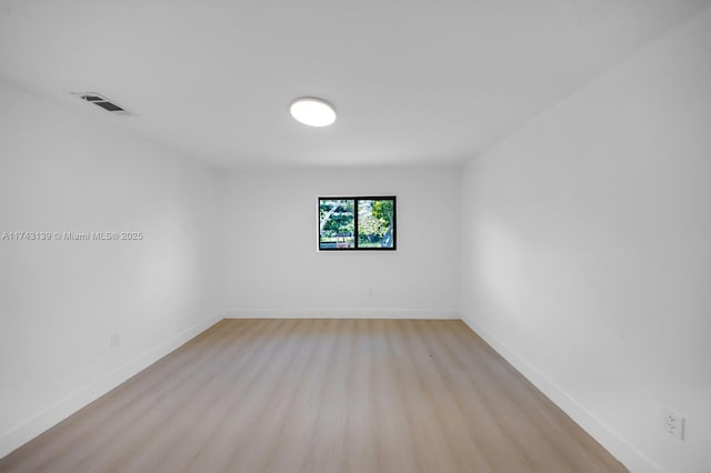 spare room featuring light wood-style floors, visible vents, and baseboards