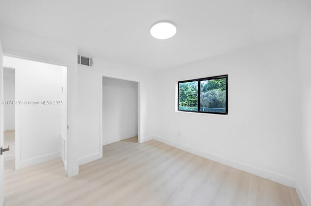 unfurnished bedroom featuring light wood finished floors, a closet, visible vents, and baseboards