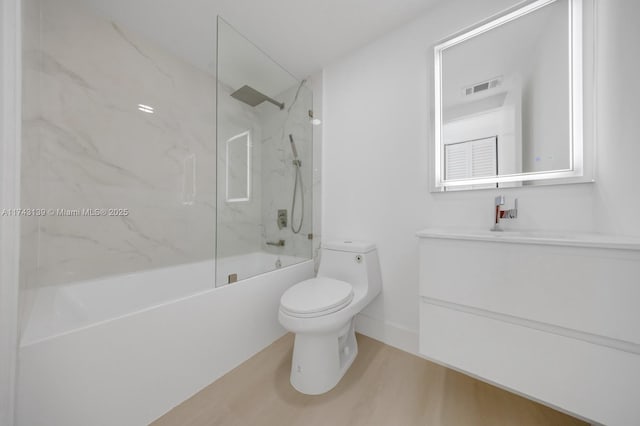 full bath with visible vents, toilet, washtub / shower combination, vanity, and wood finished floors