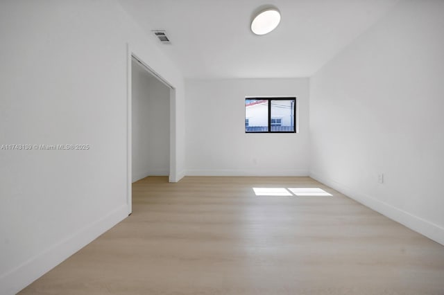 empty room featuring baseboards, visible vents, and light wood-style floors