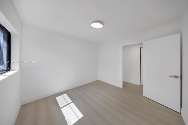 empty room with light wood-type flooring and baseboards