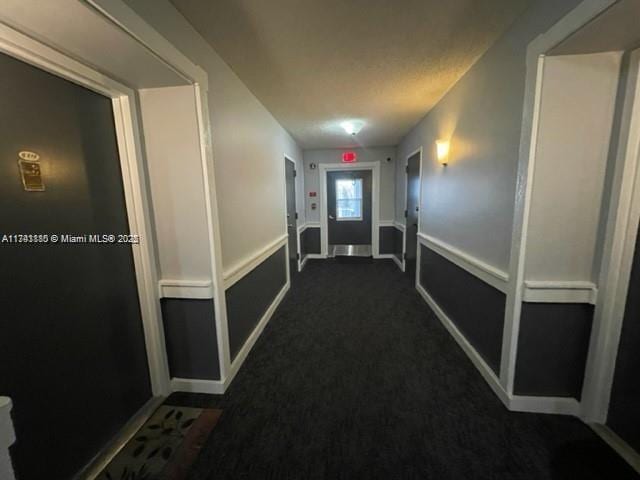 hallway with dark colored carpet