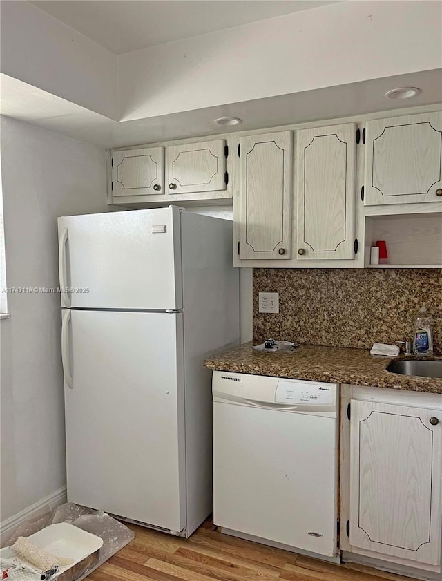 kitchen with tasteful backsplash, light wood-type flooring, sink, and white appliances