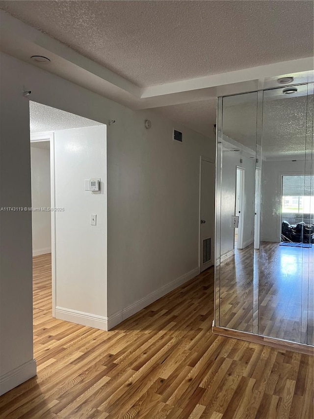 empty room with wood-type flooring and a textured ceiling