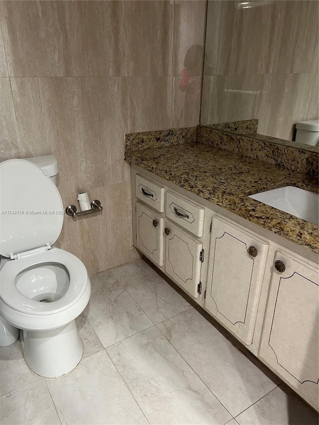 bathroom with vanity, tile walls, and toilet