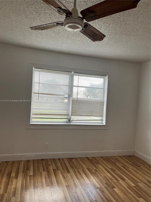 spare room with ceiling fan, plenty of natural light, hardwood / wood-style floors, and a textured ceiling