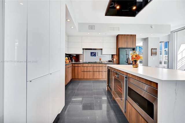 kitchen featuring white cabinetry, wine cooler, stainless steel microwave, and fridge