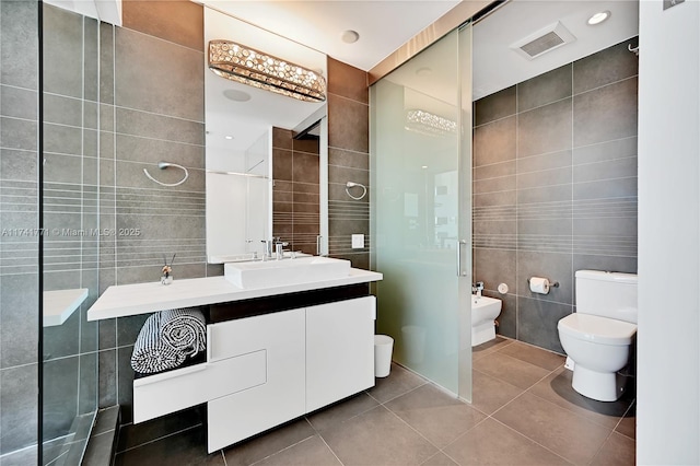 bathroom featuring toilet, tile walls, a bidet, vanity, and tile patterned flooring