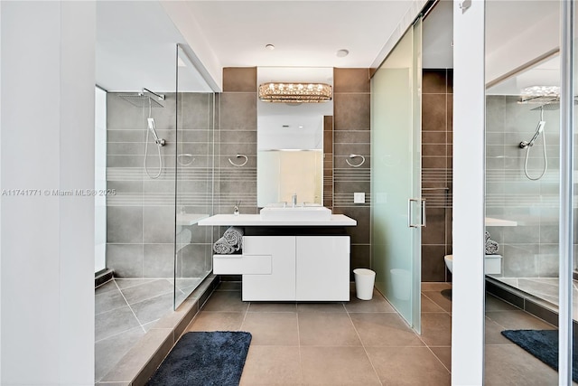 bathroom featuring tile patterned flooring, vanity, tile walls, and a shower with shower door