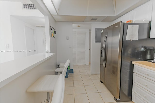 kitchen featuring white cabinetry, stainless steel fridge, and light tile patterned flooring