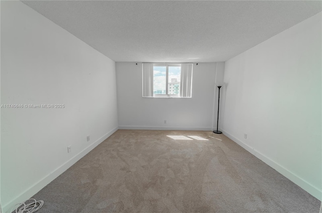 spare room featuring light carpet and a textured ceiling