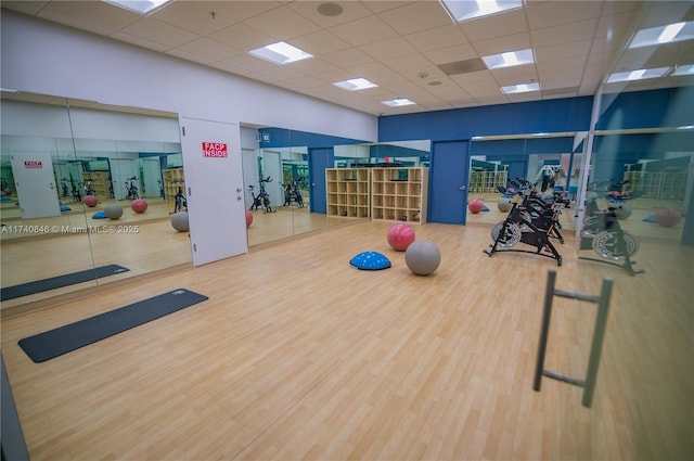 workout area featuring a paneled ceiling, hardwood / wood-style floors, and a towering ceiling