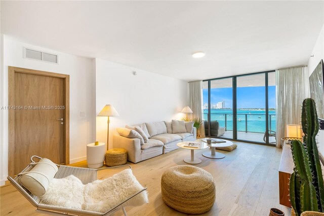 1135 103rd St Unit 602, Bay Harbor Islands, FL 33154 - living area with wood finished floors, a wall of windows, and a water view