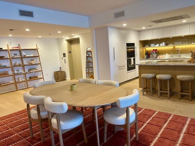 dining room featuring sink, elevator, and light hardwood / wood-style flooring