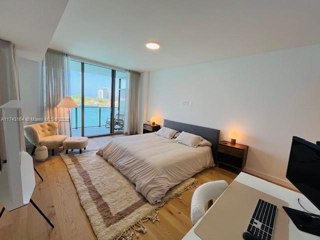 bedroom featuring expansive windows, access to exterior, and light wood-type flooring