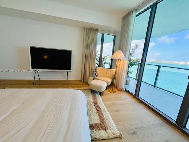 bedroom featuring light hardwood / wood-style flooring, a water view, and access to outside