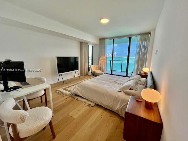 bedroom with access to exterior, a wall of windows, and wood-type flooring