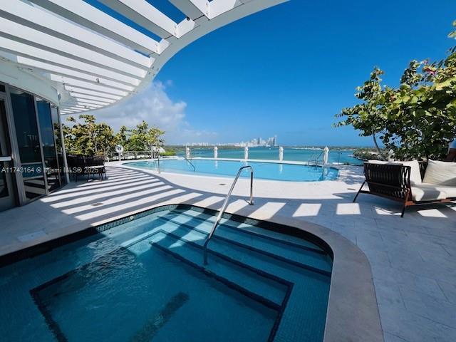 view of pool with a patio area and a water view