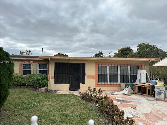 view of front facade featuring a front lawn, a patio area, and stucco siding