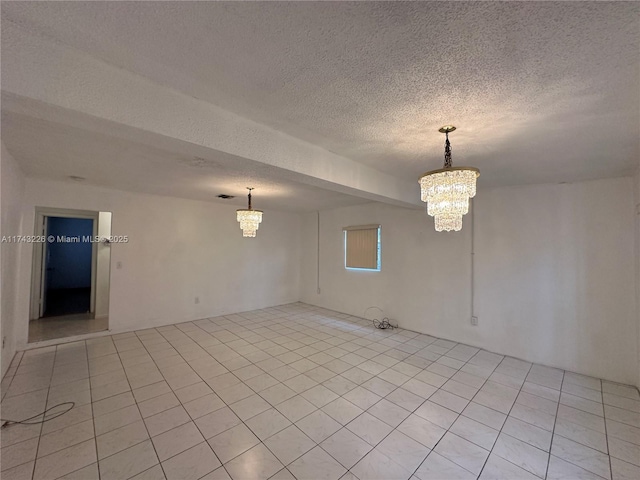 unfurnished room with a textured ceiling, visible vents, a notable chandelier, and light tile patterned flooring