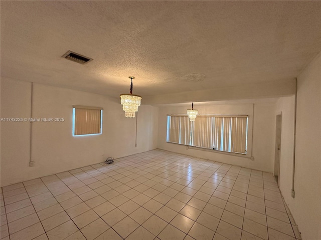 unfurnished room with an inviting chandelier, visible vents, a textured ceiling, and light tile patterned flooring