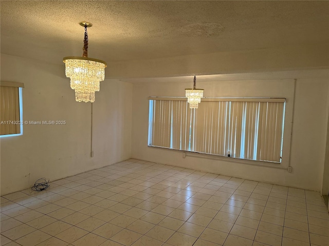 unfurnished room featuring a textured ceiling, light tile patterned flooring, and a notable chandelier