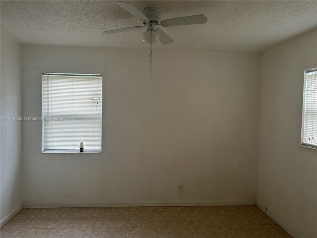 unfurnished room featuring a textured ceiling, a ceiling fan, and baseboards