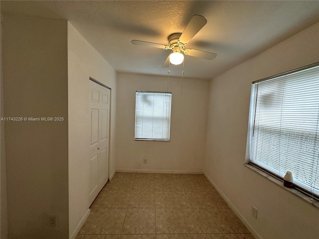 empty room featuring a wealth of natural light, baseboards, and light tile patterned floors