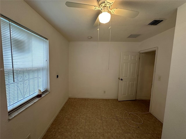 tiled spare room with baseboards, visible vents, and a ceiling fan