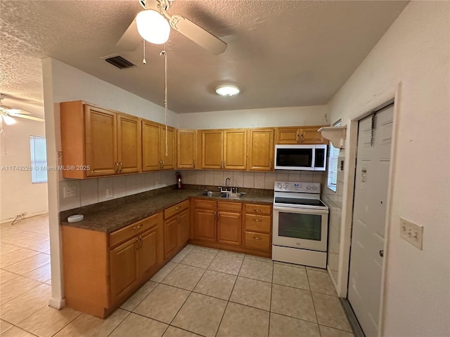 kitchen featuring white range with electric cooktop, decorative backsplash, a ceiling fan, dark countertops, and a sink